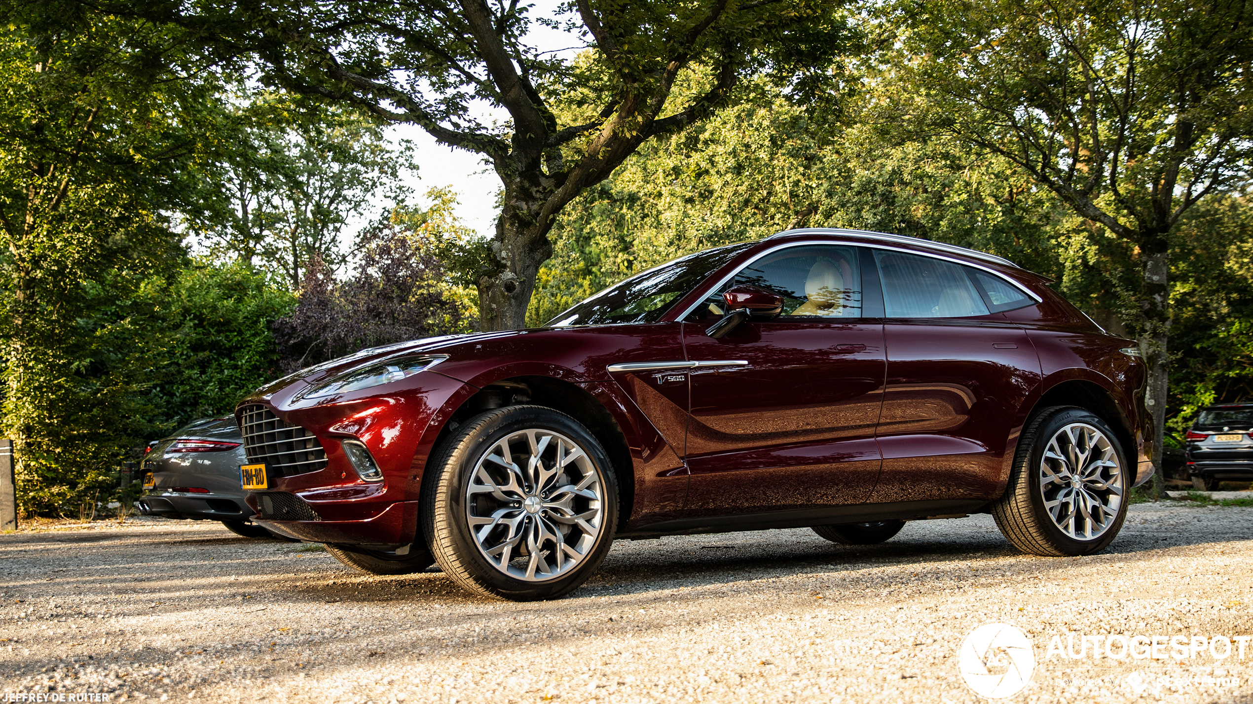 Donkerrode Aston Martin DBX kleurt wel in het avondzonnetje